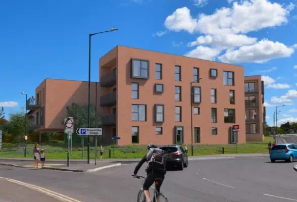 Modern brick apartment building near roundabout and cyclist.