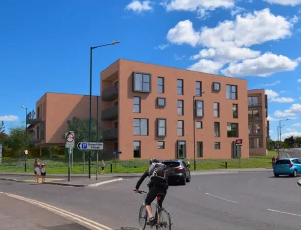 Modern brick apartment building near roundabout and cyclist.
