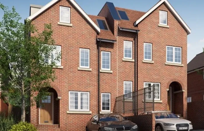 Modern brick townhouse with parked cars and trees.