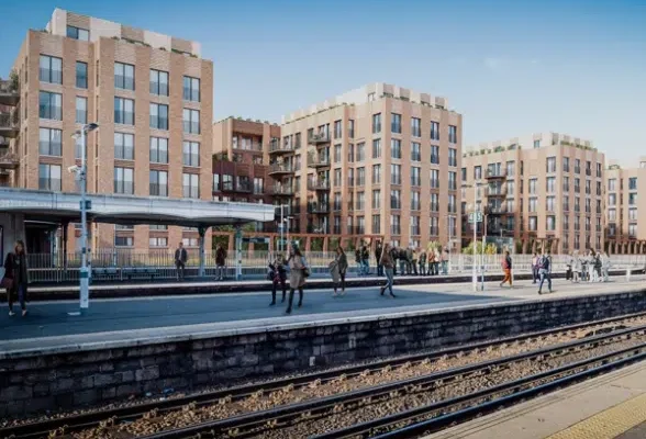 Modern flats beside train station platform, people walking.