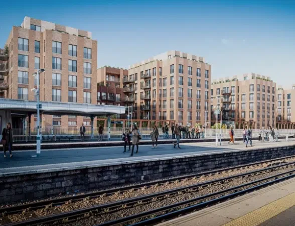 Modern flats beside train station platform, people walking.
