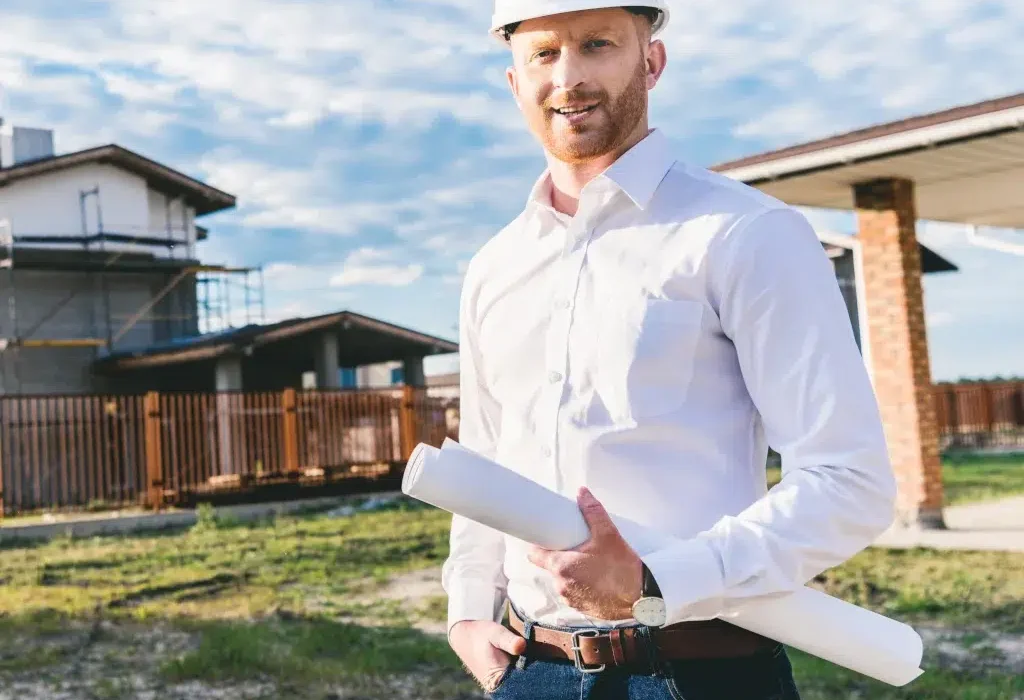 Architect with blueprints at construction site outdoors.