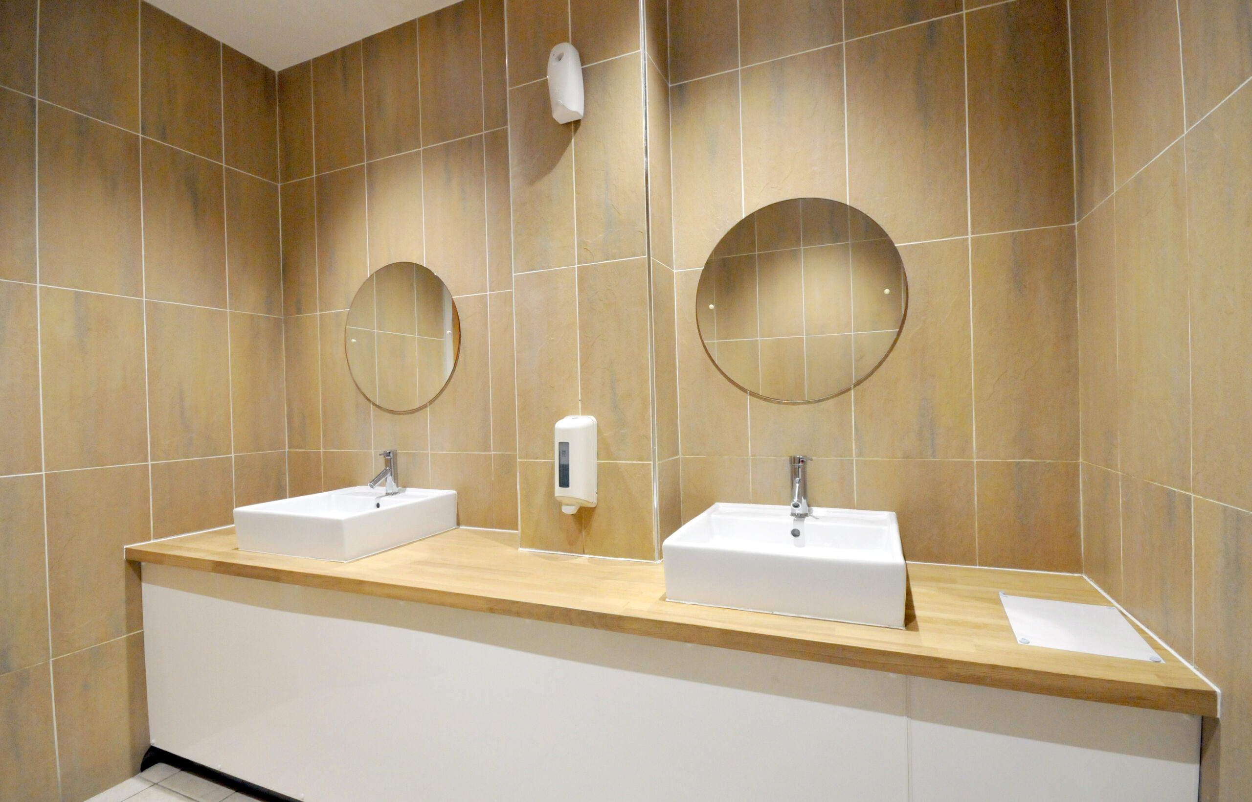Modern bathroom with twin sinks and round mirrors.