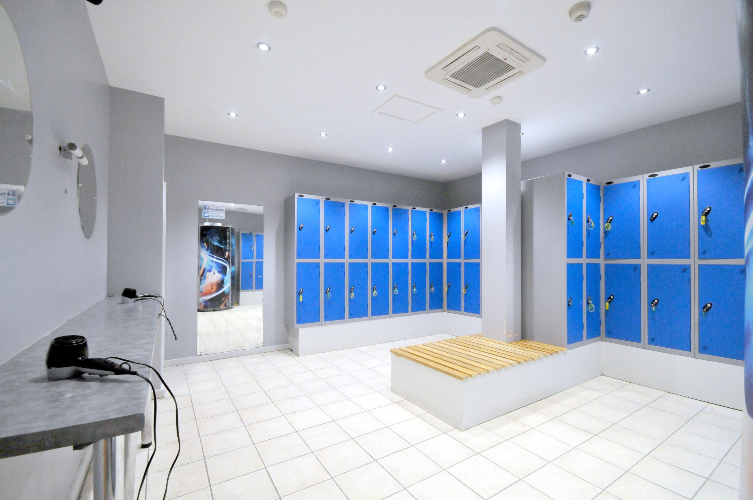 Modern locker room with blue lockers and benches.