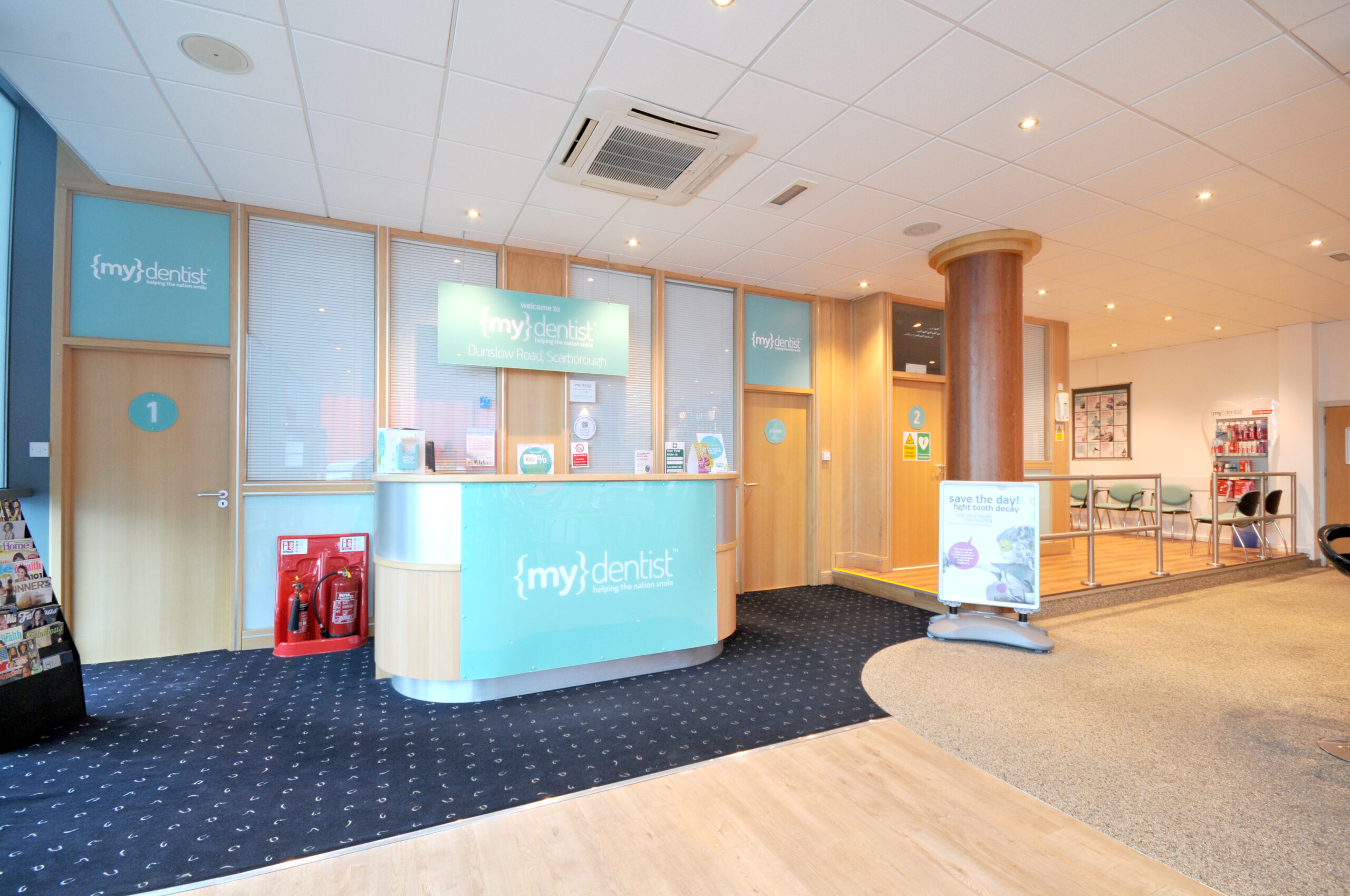 Dental clinic reception area with seating and signage.