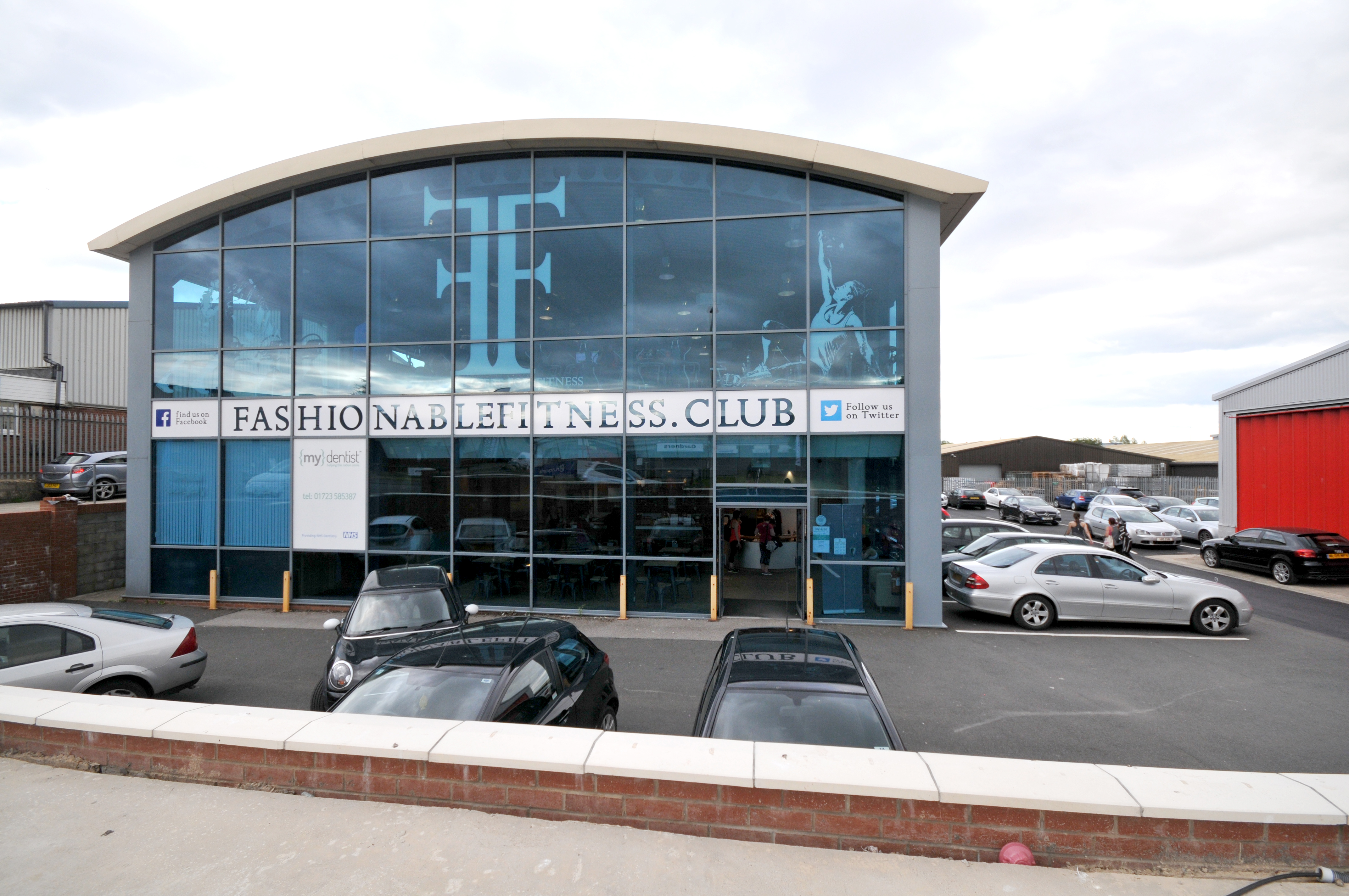 Fashionable Fitness Club building exterior with cars parked.