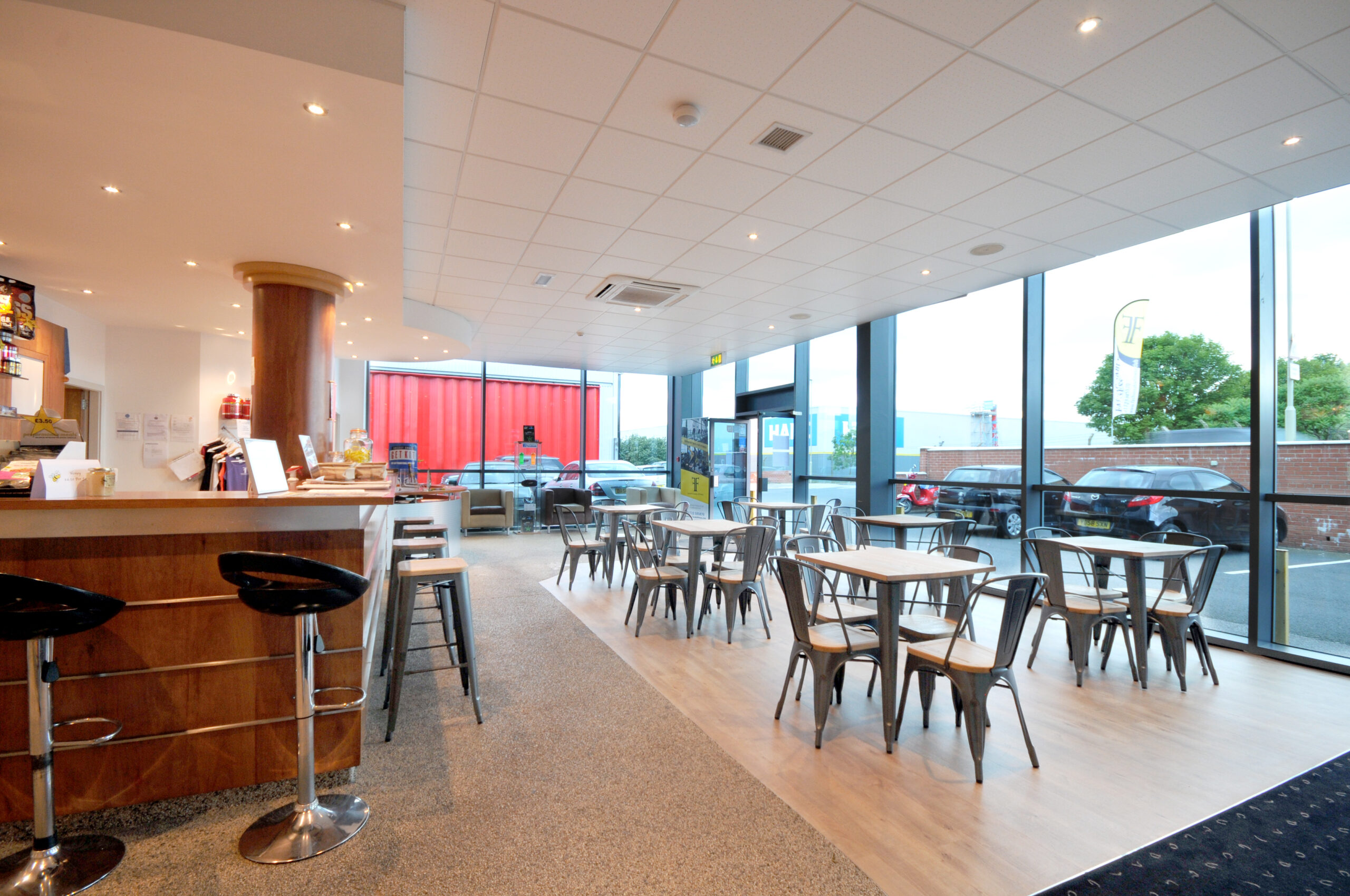 Modern cafe area with tables and large windows.
