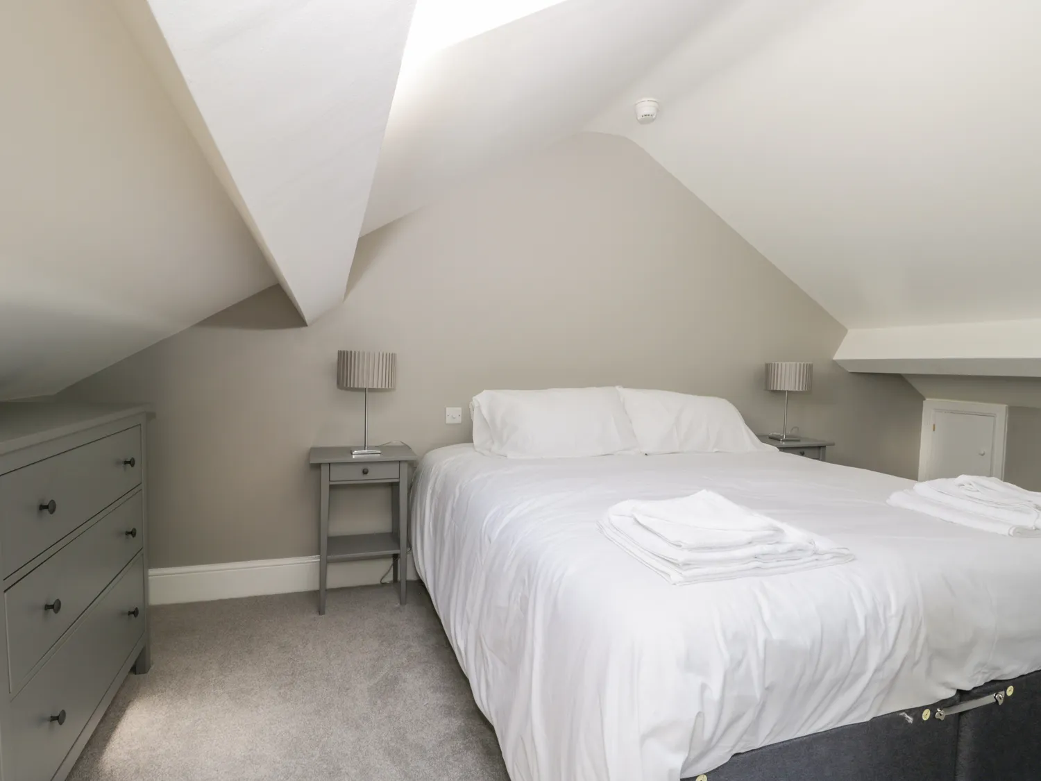 Attic bedroom with double bed and grey furniture.