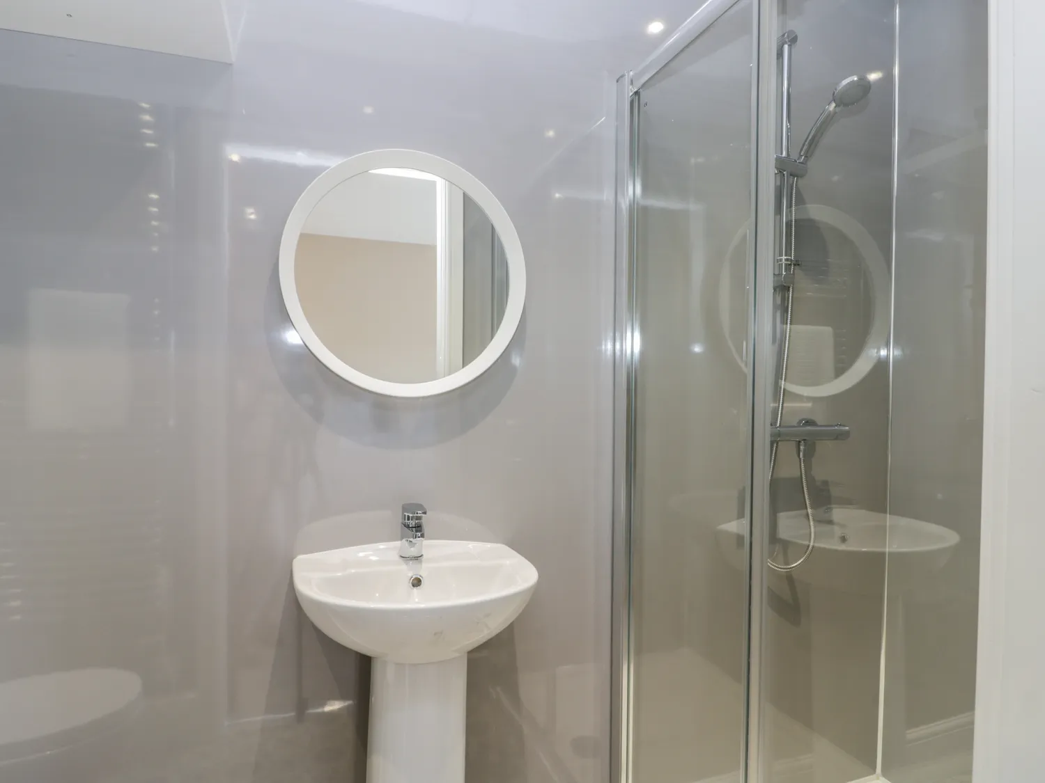 Modern bathroom with round mirror and glass shower