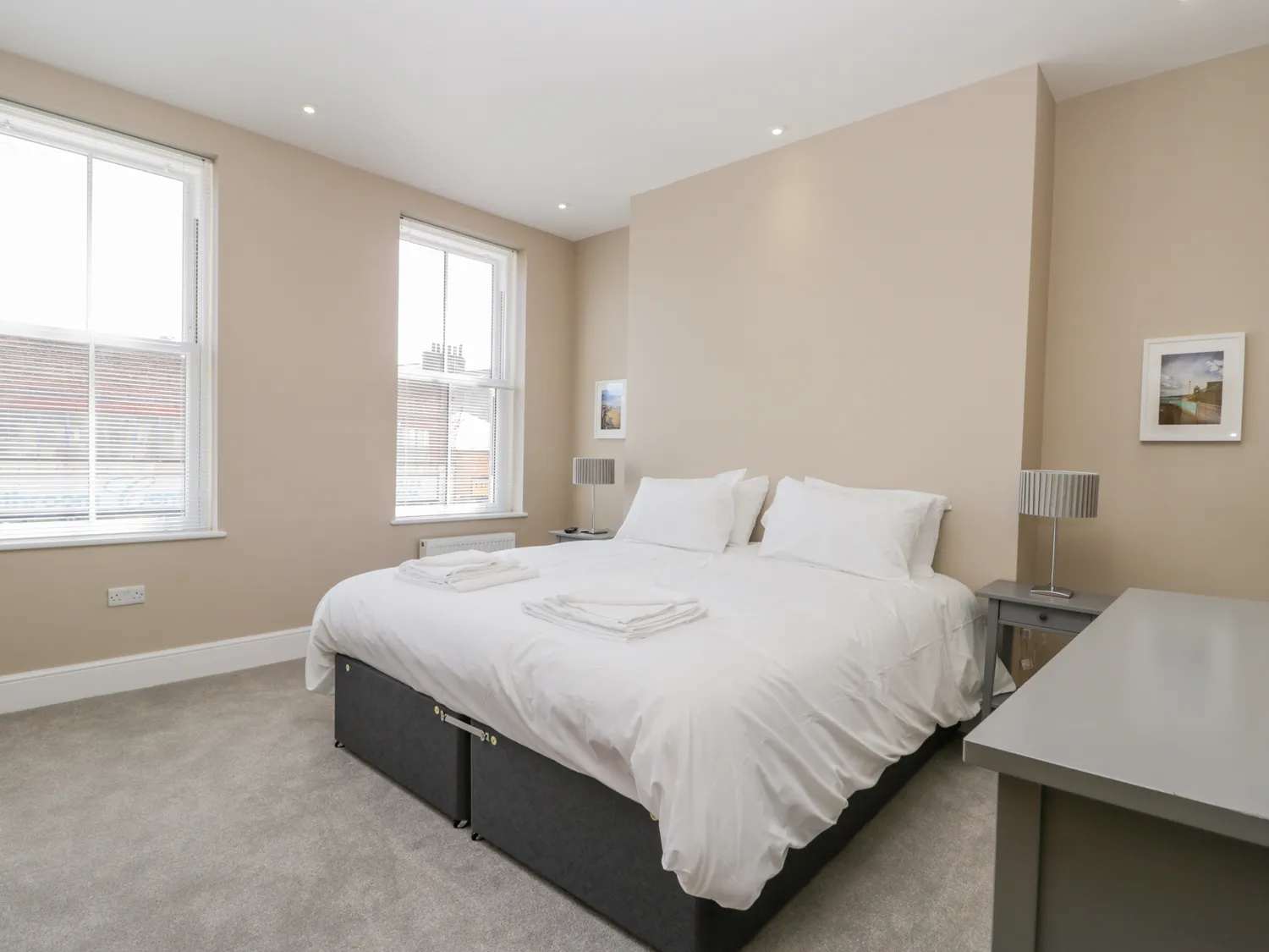 Bright bedroom with double bed and large windows.