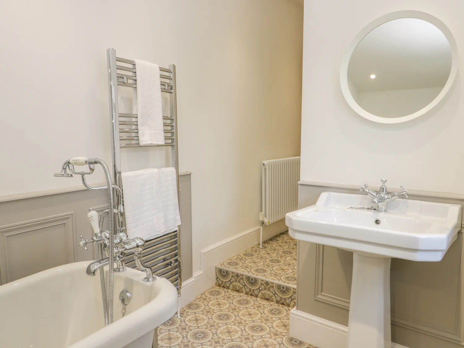 Elegant bathroom with freestanding tub and pedestal sink.