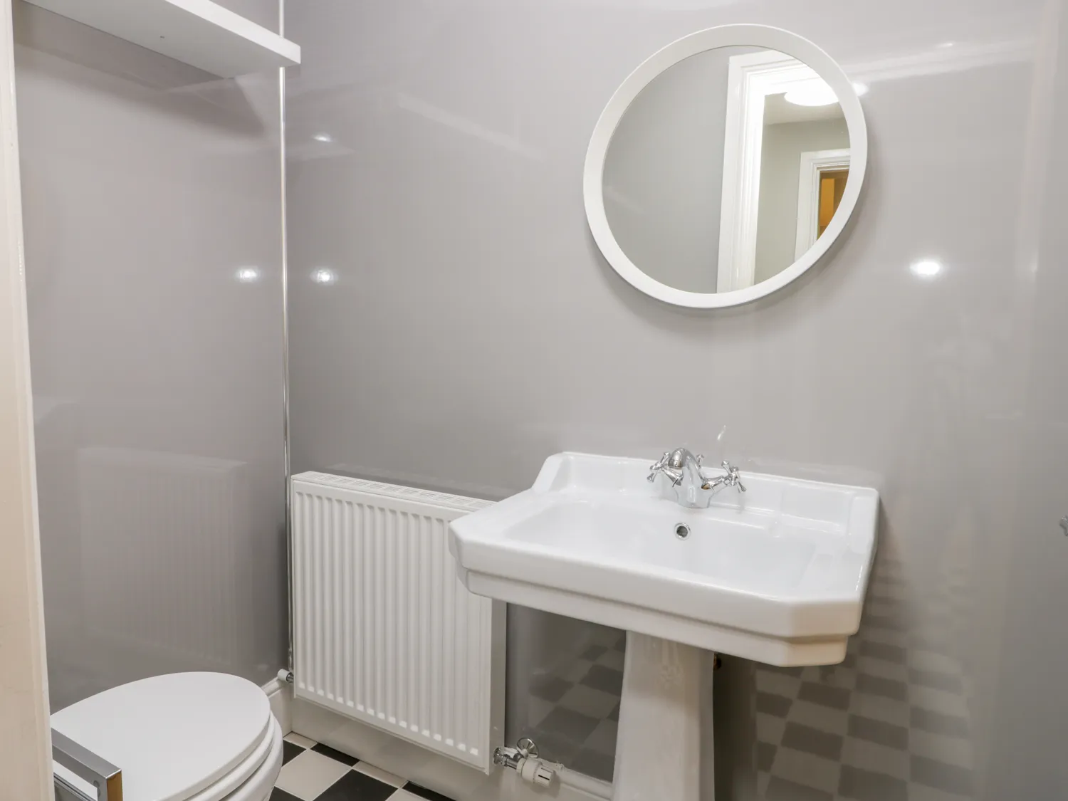 Modern bathroom with grey walls and round mirror.