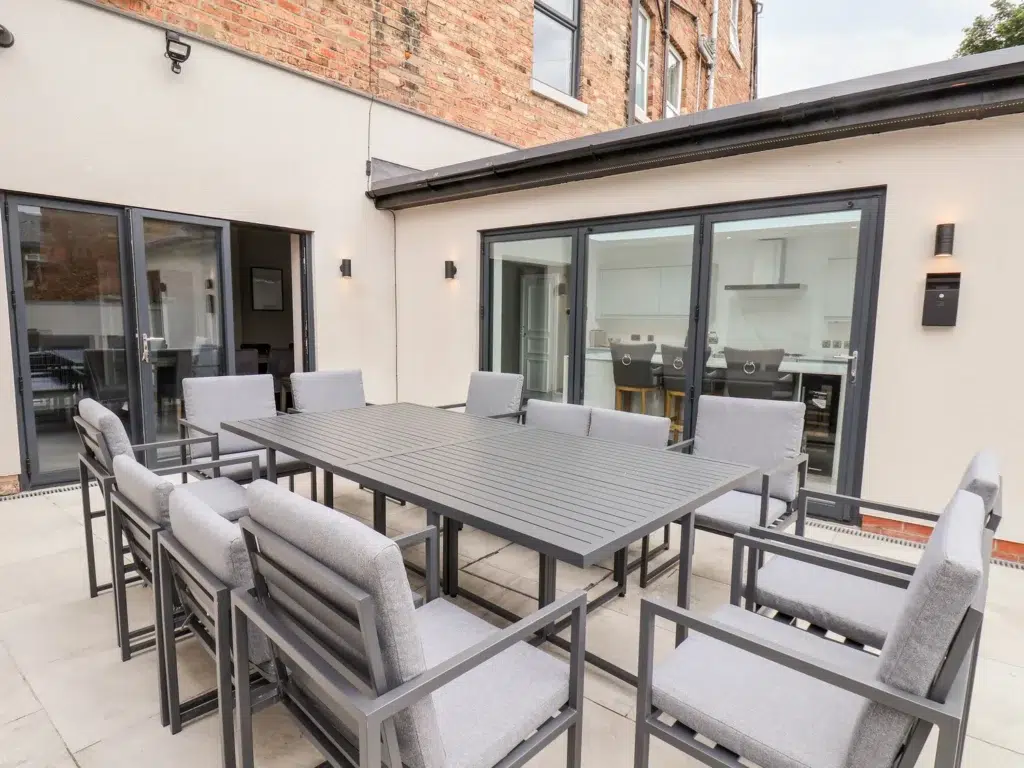 Modern patio with grey outdoor furniture and large windows.