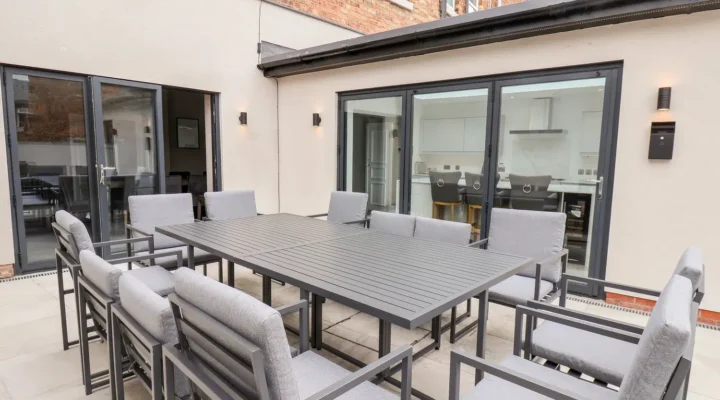 Modern patio with grey outdoor furniture and large windows.