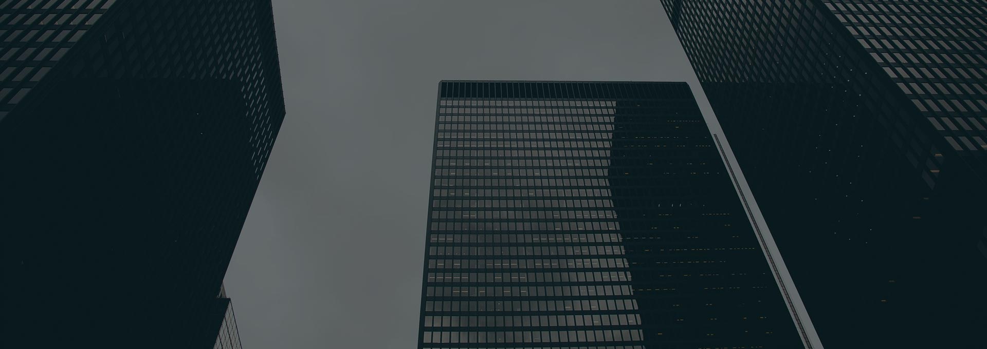 Dark skyscrapers against a cloudy sky